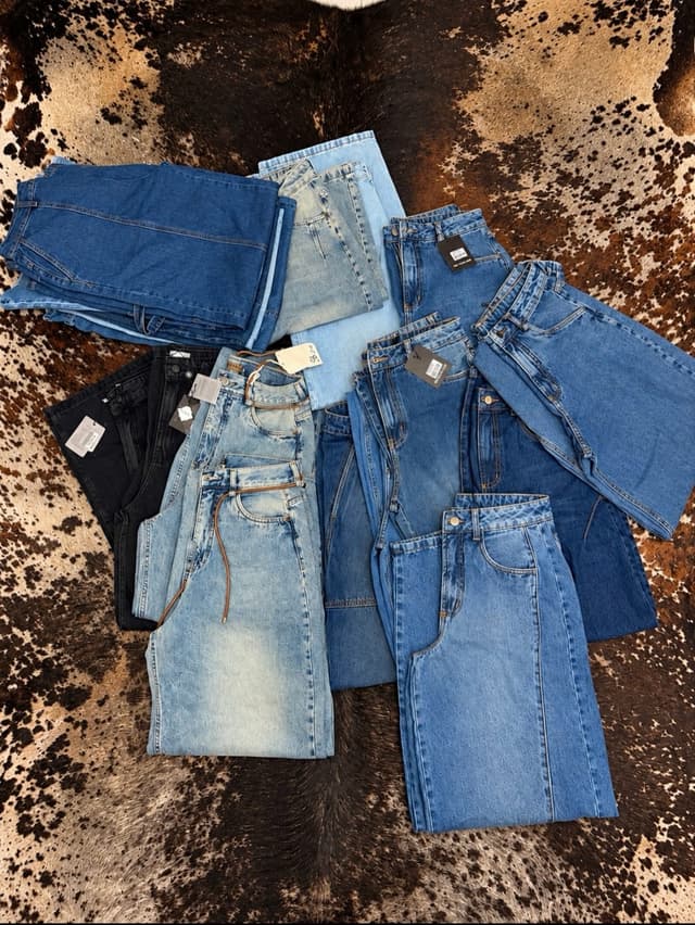 Calças jeans de várias lavagens dobradas sobre um tapete de couro