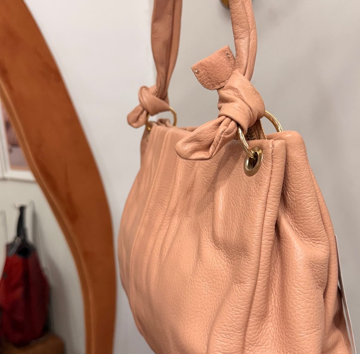 Bolsa Jorge Bischoff rosa nude pendurada na loja, mostrando o nó das alças